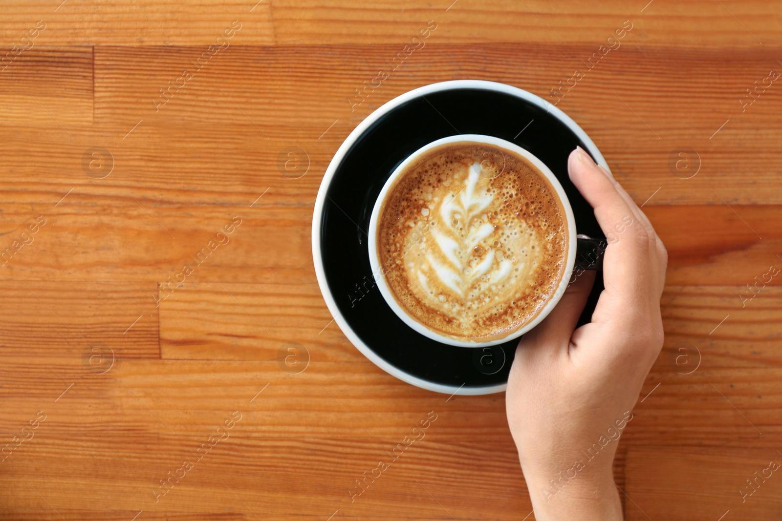 Photo of Woman with cup of fresh aromatic coffee at wooden table, top view