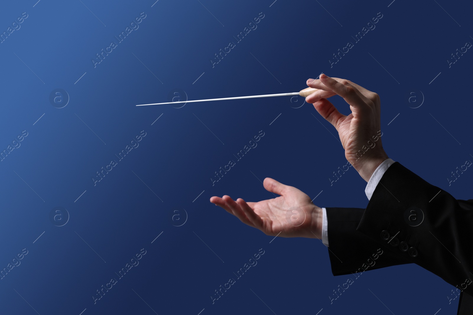 Photo of Professional conductor with baton on blue background, closeup