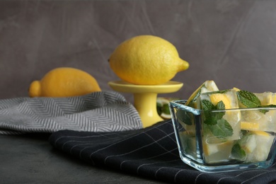 Photo of Ice cubes with mint and lemon in bowl on table. Space for text