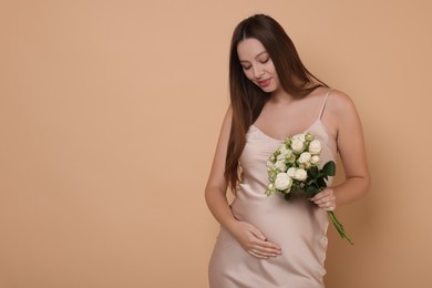 Photo of Beautiful pregnant woman in dress with bouquet of roses on beige background, space for text