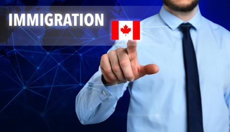 Immigration. Businessman touching digital screen with word and flag of Canada on dark blue background, closeup