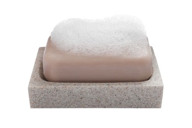Soap bar with fluffy foam in holder on white background