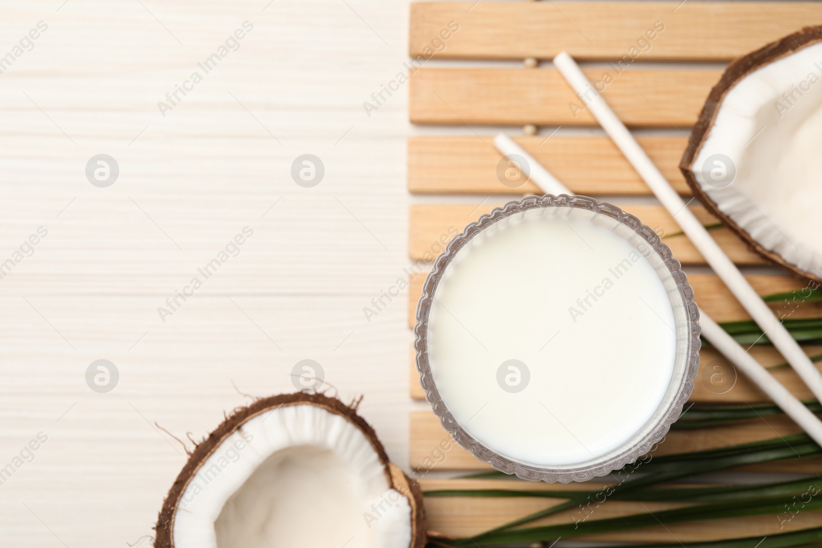 Photo of Glass of delicious vegan milk and coconuts on white wooden table, flat lay. Space for text