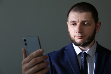 Photo of Man unlocking smartphone with facial scanner on grey background. Biometric verification