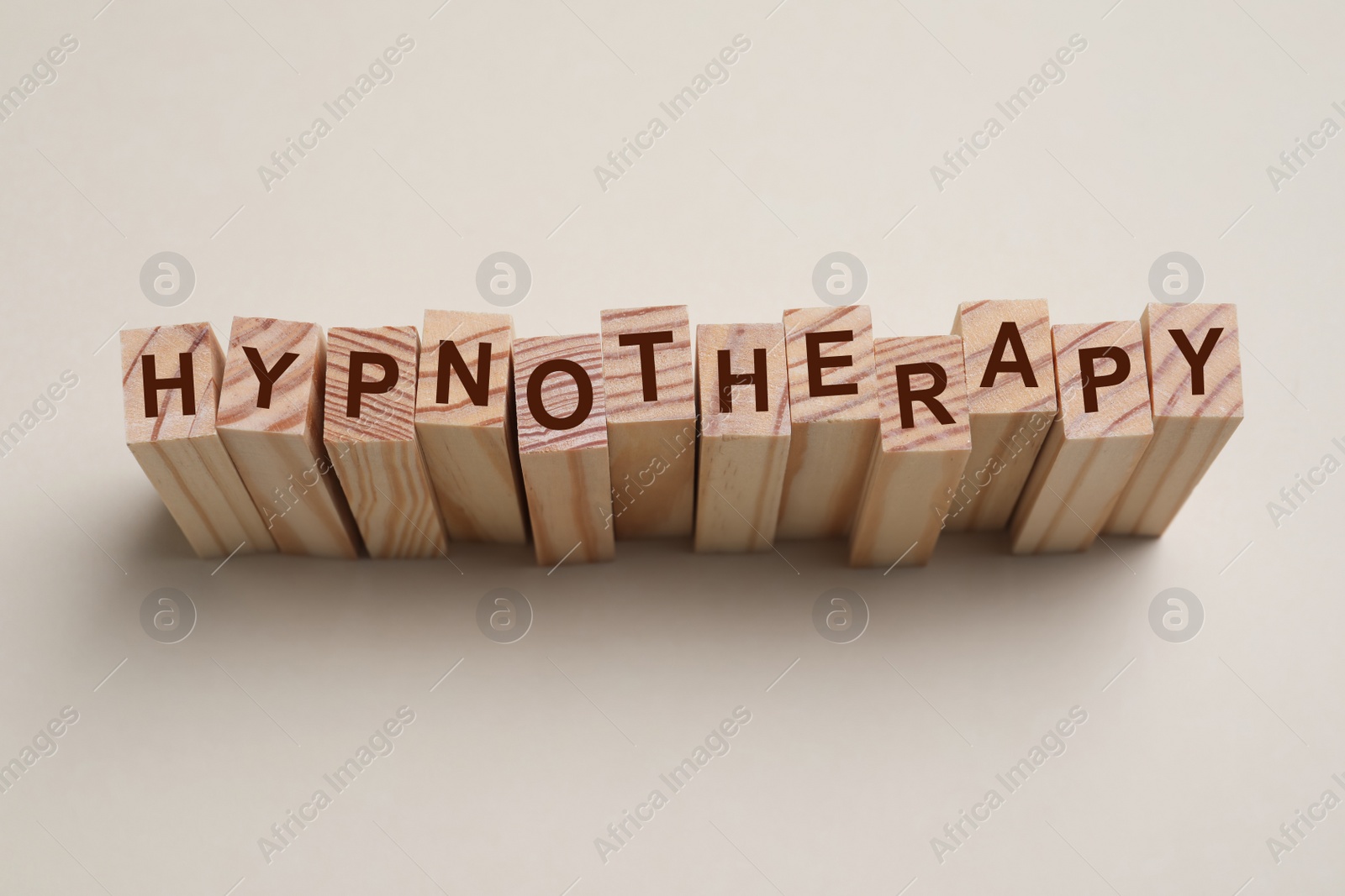 Photo of Wooden blocks with word HYPNOTHERAPY on beige background, above view