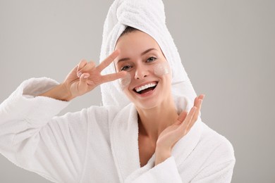 Photo of Woman with cosmetic product on her face against grey background. Spa treatments