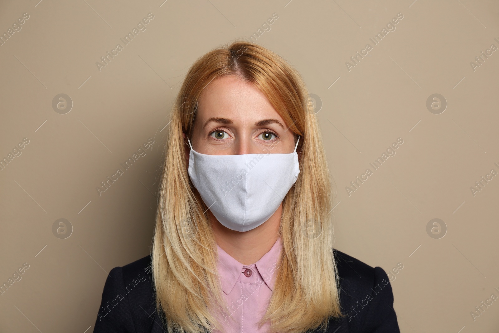 Photo of Woman wearing handmade cloth mask on beige background. Personal protective equipment during COVID-19 pandemic