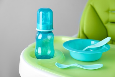 Photo of Set of plastic dishware on white feeding table. Serving baby food