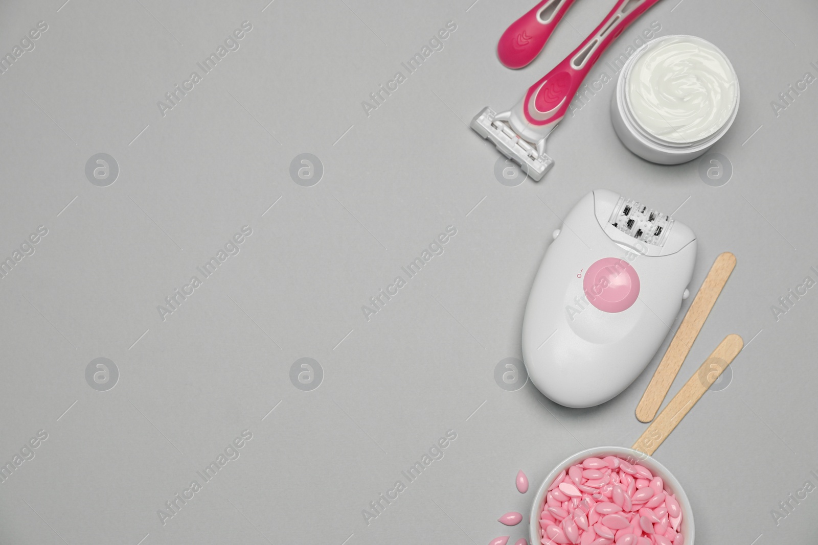 Photo of Modern epilator and other hair removal products on light grey background. Space for text