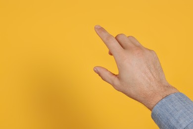 Photo of Man pointing at something against yellow background, closeup on hand. Space for text