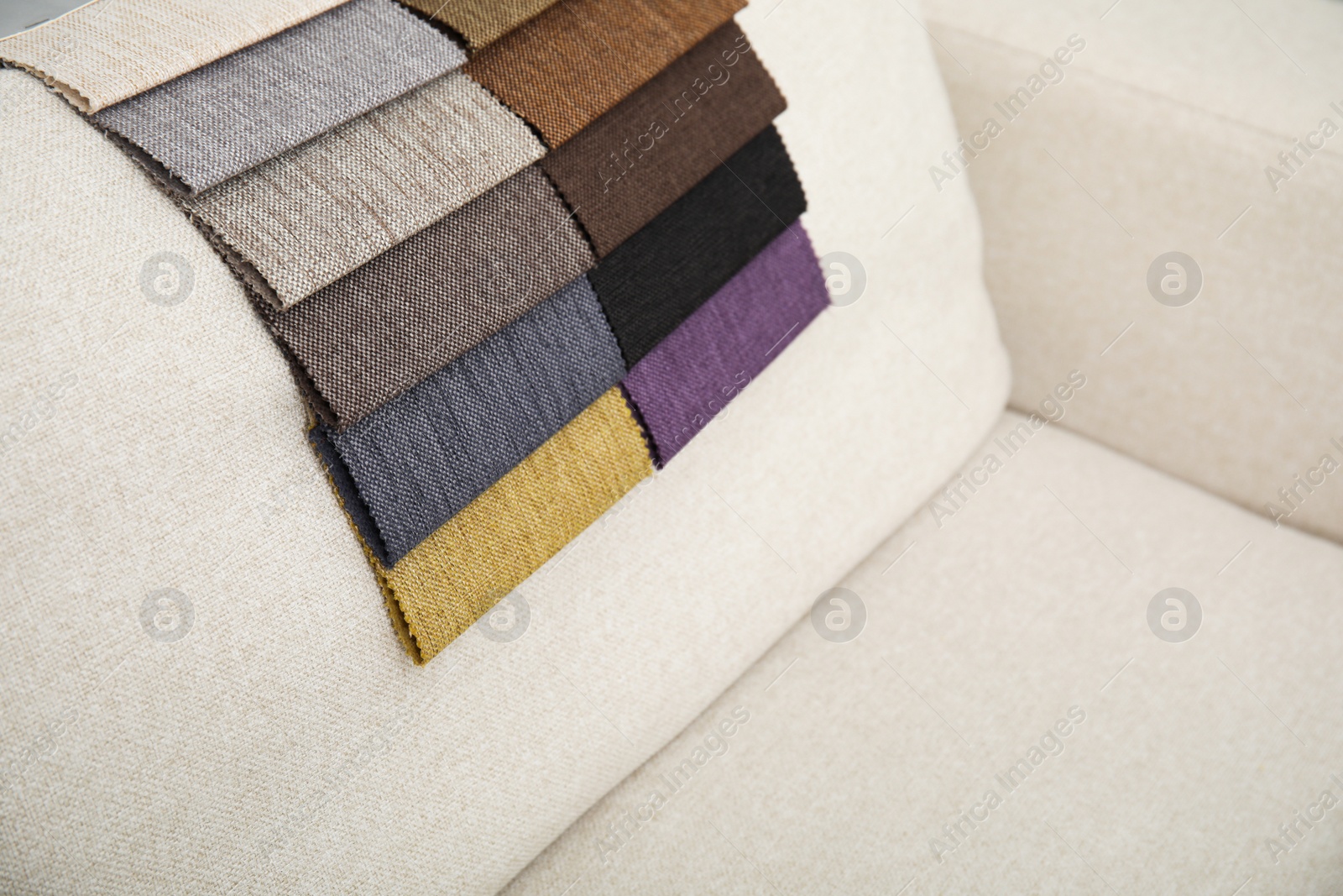 Photo of Catalog of colorful fabric samples on beige sofa