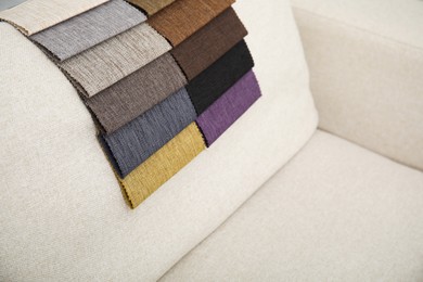 Photo of Catalog of colorful fabric samples on beige sofa