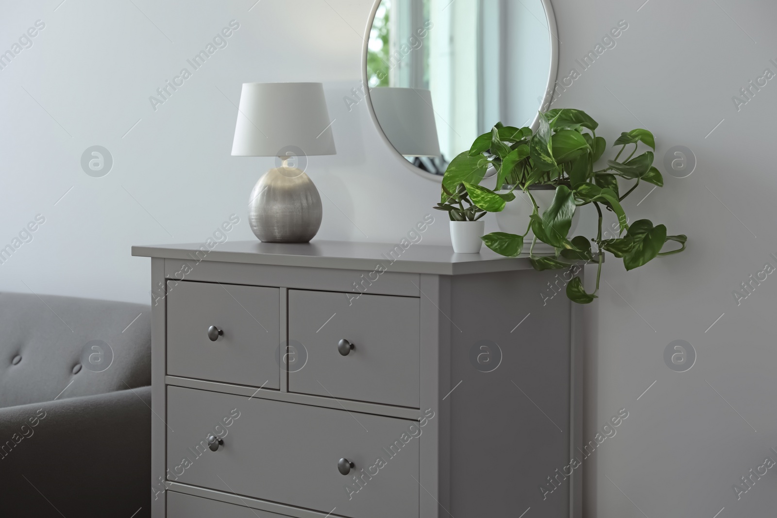 Photo of Stylish room interior with round mirror on wall over chest of drawers