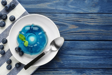 Photo of Plate of delicious blue jelly with berries on color wooden background, flat lay. Space for text