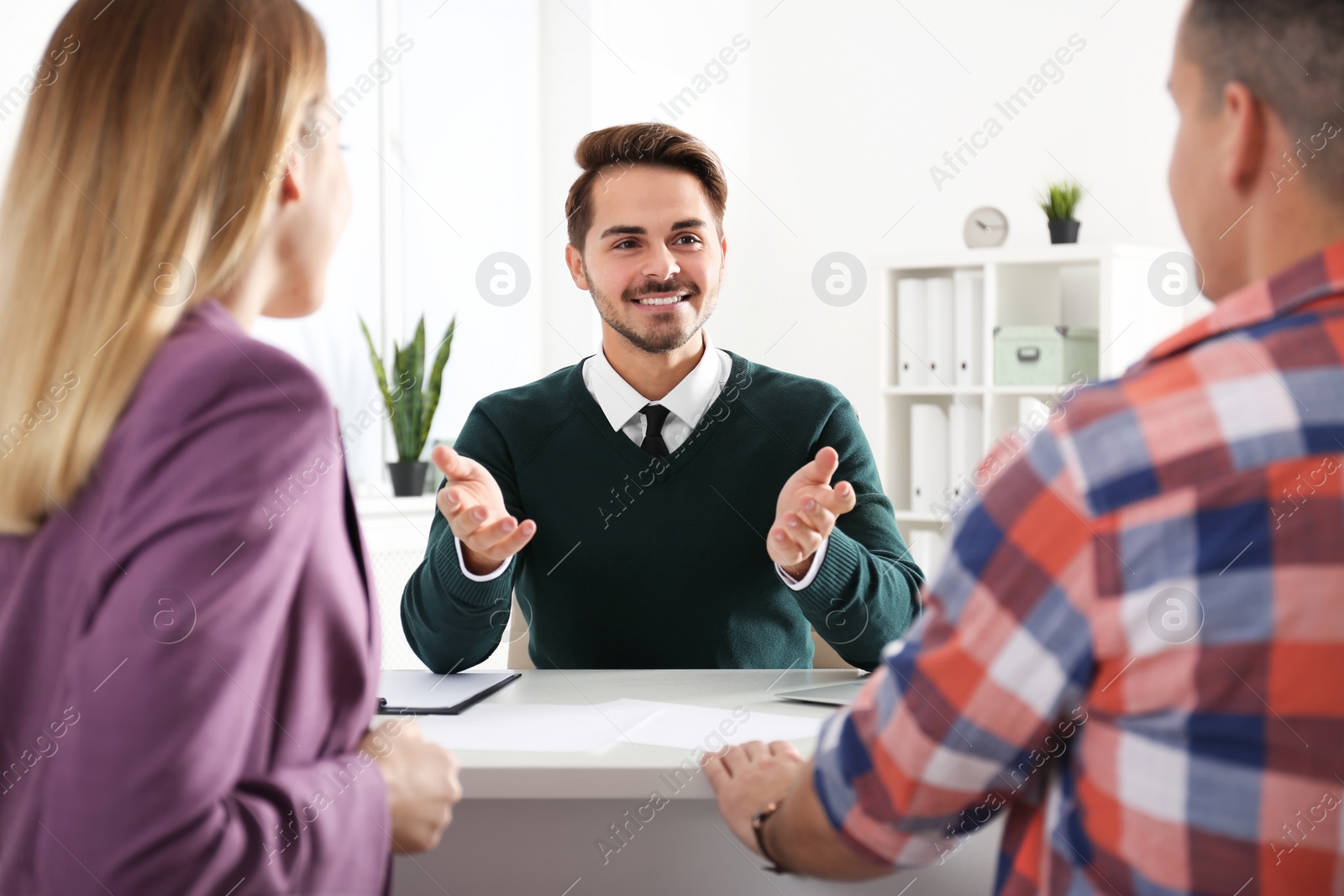 Photo of Real estate agent consulting young couple in office