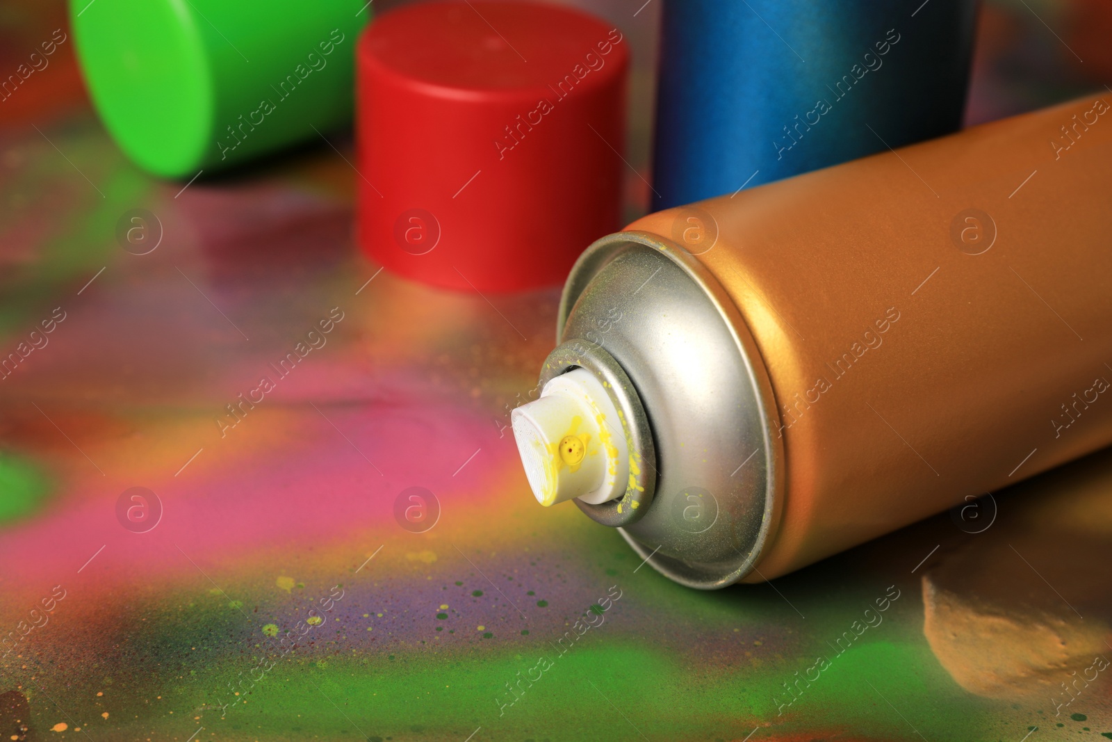 Photo of Cans of different graffiti spray paints on color background, closeup. Space for text