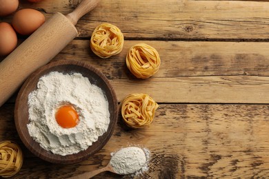 Photo of Raw noodles and ingredients on wooden table, flat lay. Space for text