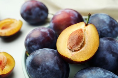 Tasty ripe plums on white table, closeup