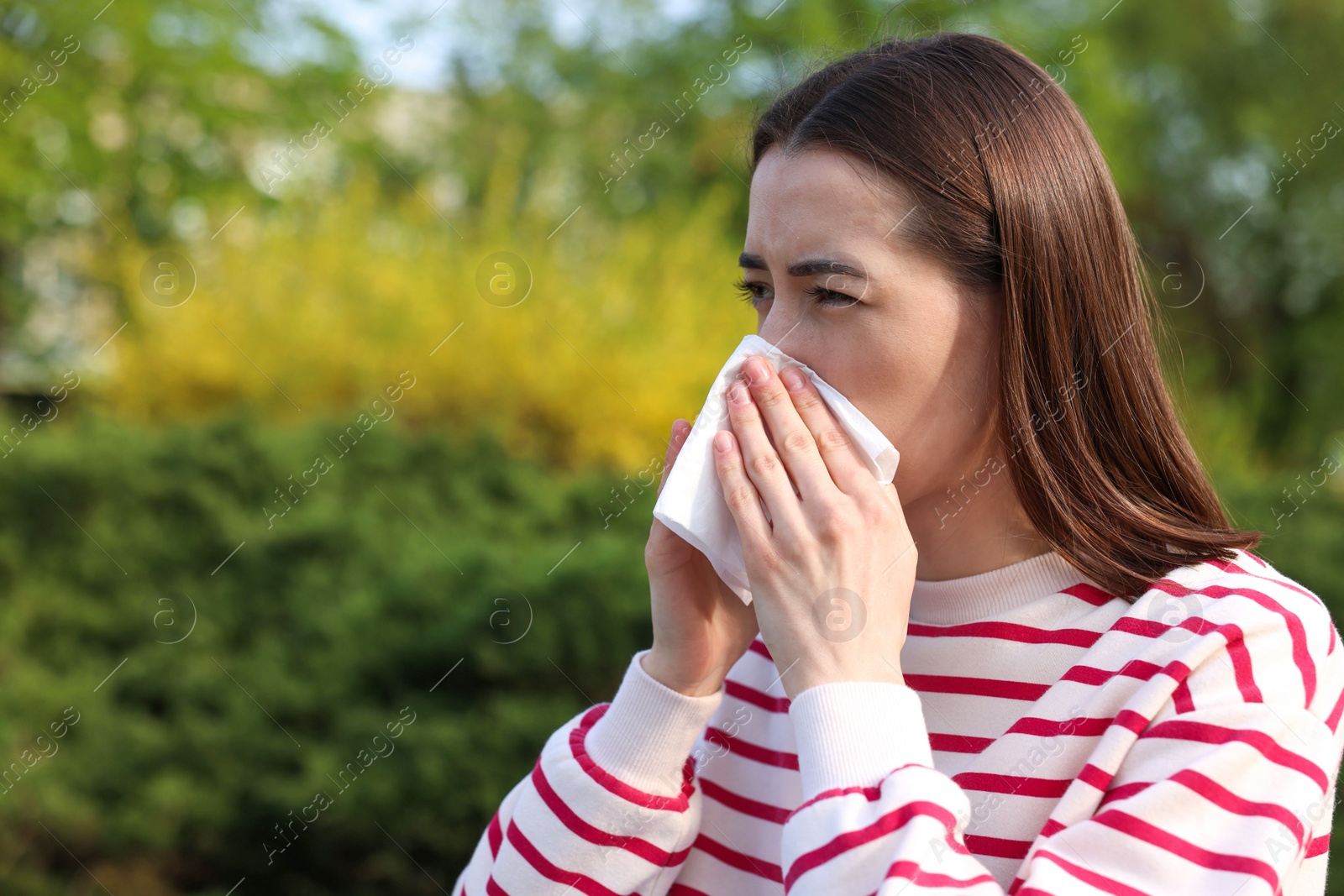 Photo of Woman with napkin suffering from seasonal allergy outdoors