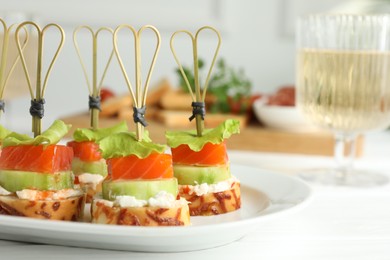 Photo of Tasty canapes with salmon, cucumber, bread and cream cheese on white table, closeup