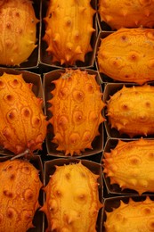 Photo of Many fresh kiwano fruits in cardboard containers, top view