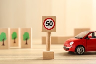 Photo of Traffic sign Maximum speed and toy car on wooden table. Passing driving license exam