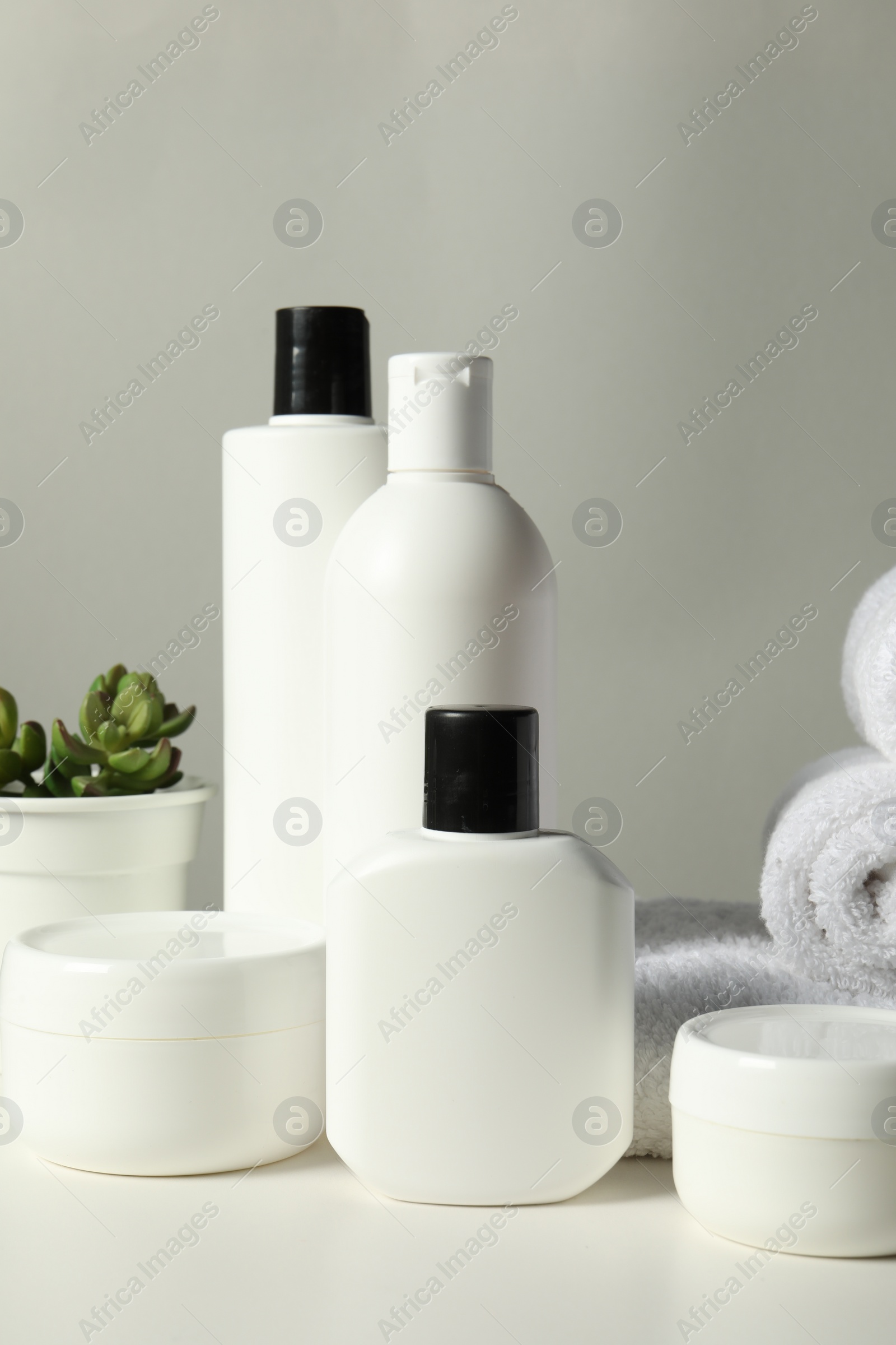 Photo of Different bath accessories, towels and houseplant on white table against grey background