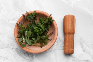 Photo of Mortar with pestle and mint leaves on light grey marble table, top view