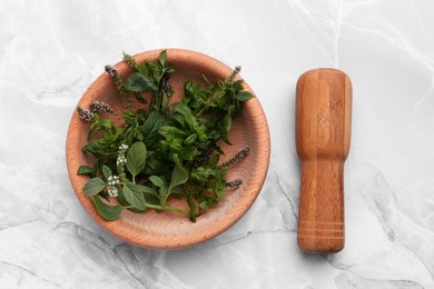 Mortar with pestle and mint leaves on light grey marble table, top view