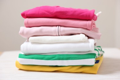 Photo of Stack of folded clothes on table against beige background