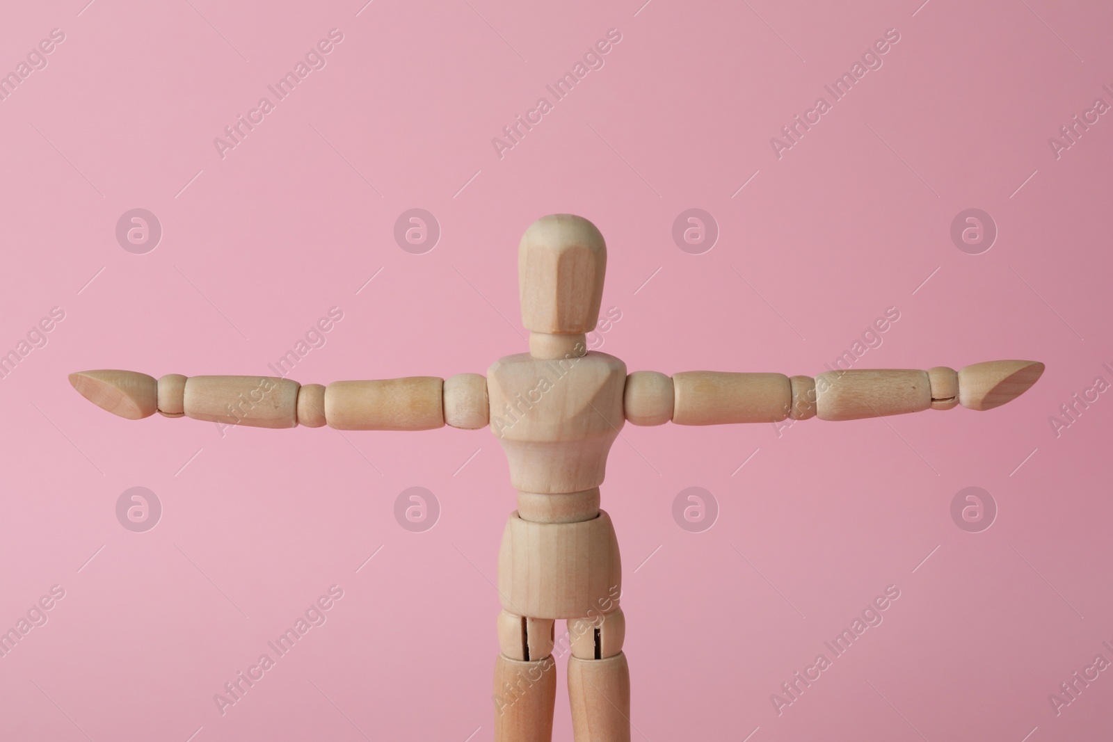 Photo of Wooden human model on pink background. Mini mannequin