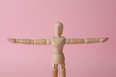 Wooden human model on pink background. Mini mannequin