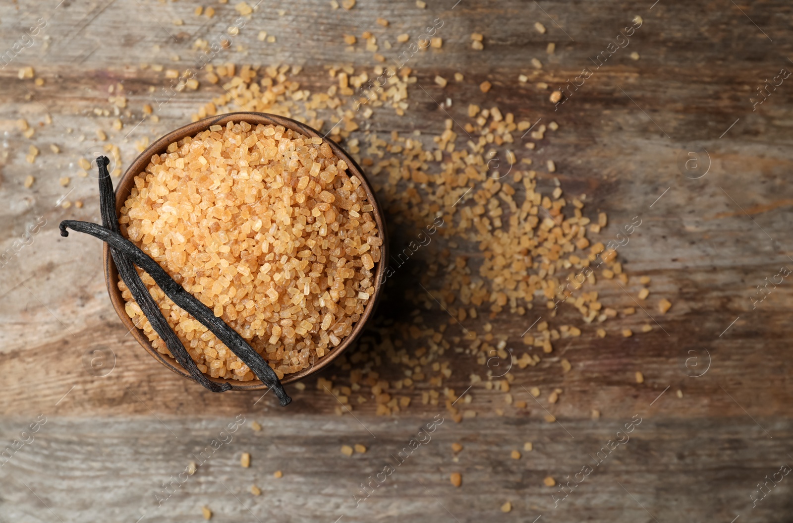 Photo of Bowl of aromatic vanilla sugar and sticks on wooden background