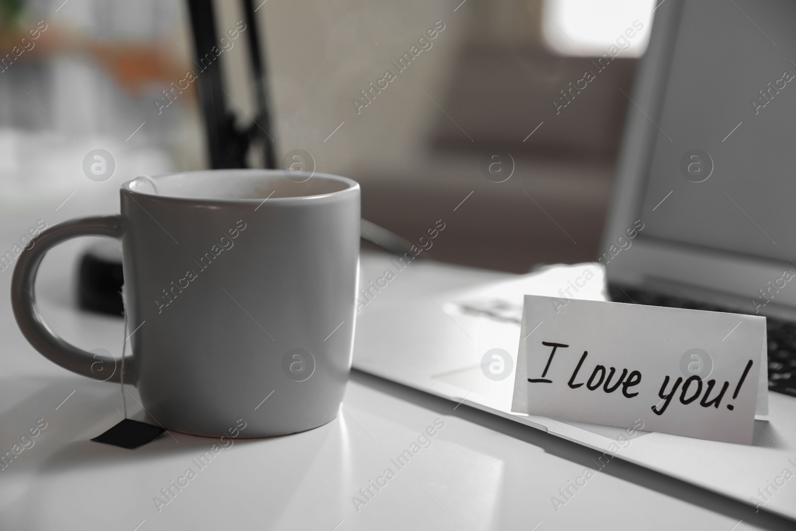 Photo of Note with handwritten text I Love You on workplace indoors. Romantic message