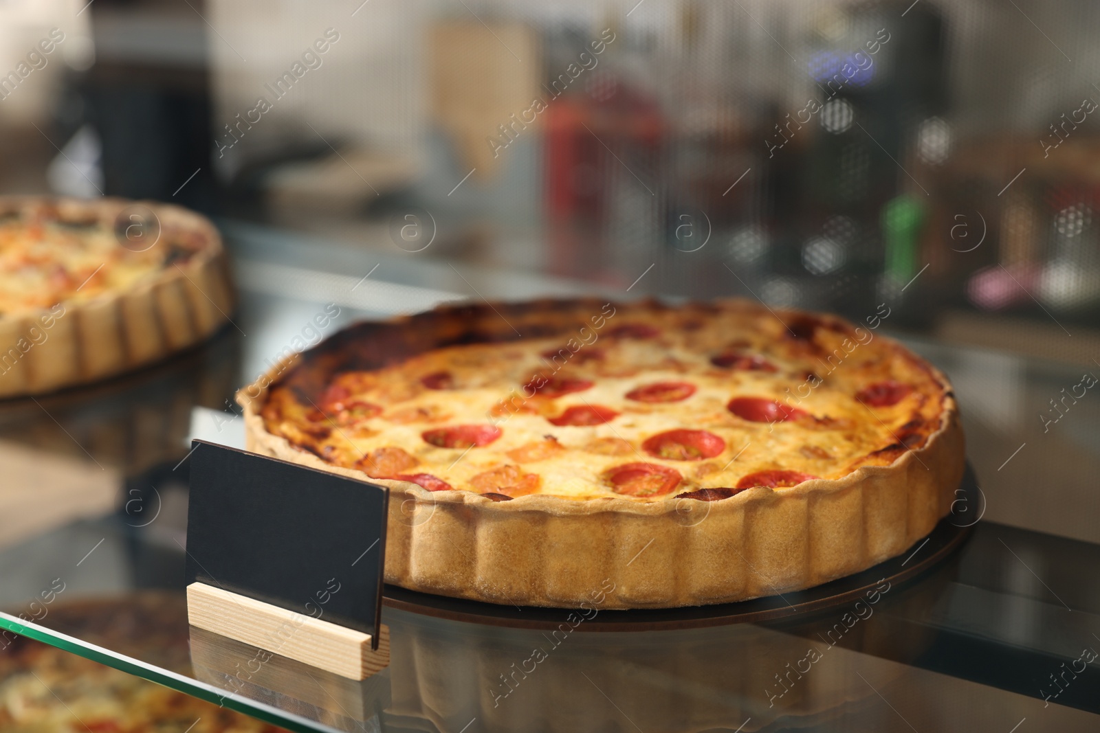 Photo of Delicious quiche with shrimps on counter in bakery shop, closeup. Space for text