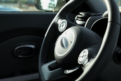 Photo of Black steering wheel inside of modern car, closeup