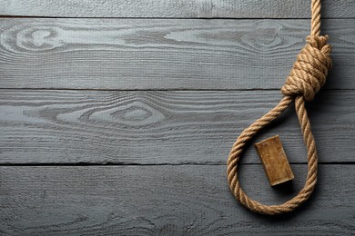 Rope noose and soap bar on grey wooden table, flat lay. Space for text