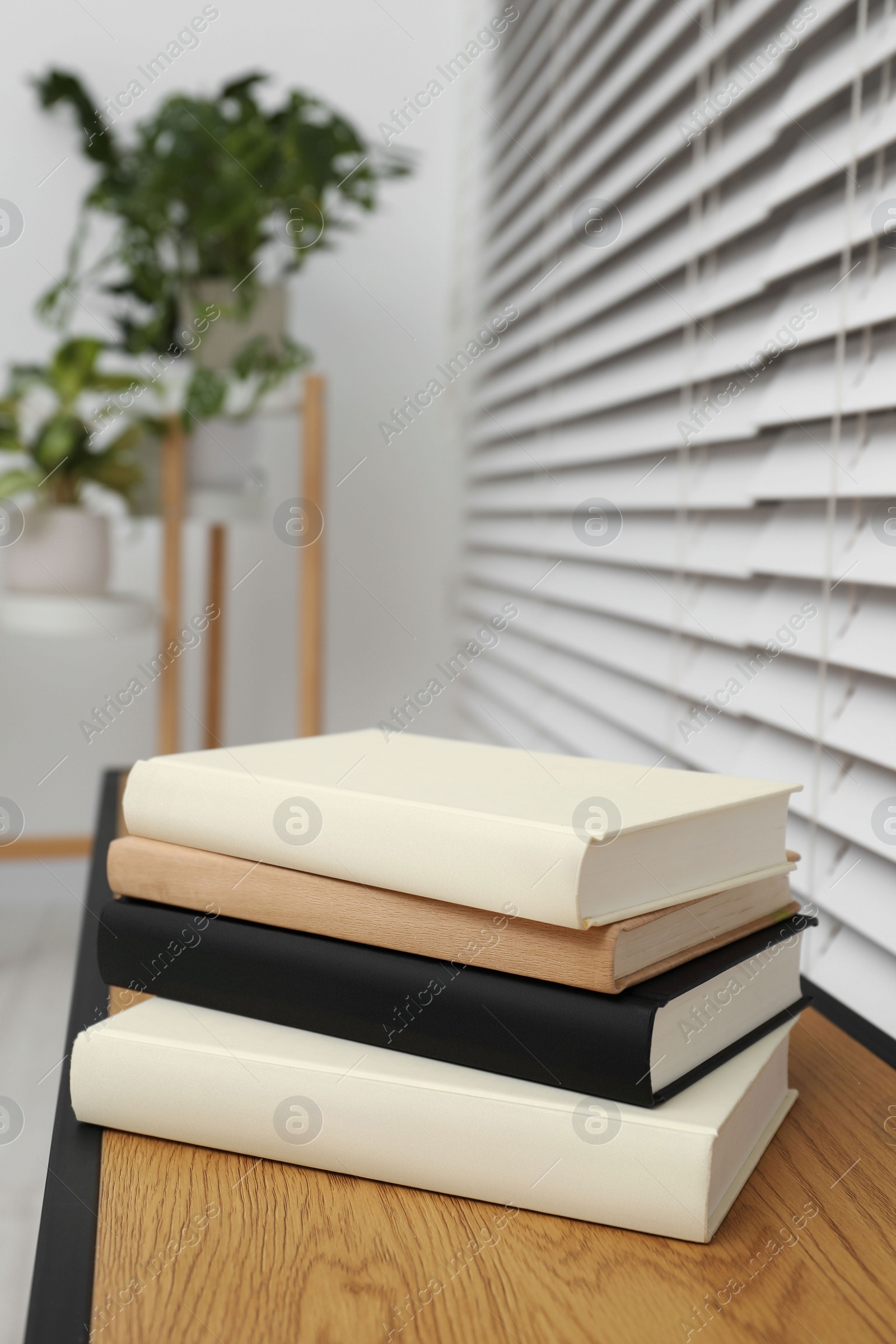 Photo of Stack of hardcover books on wooden table indoors