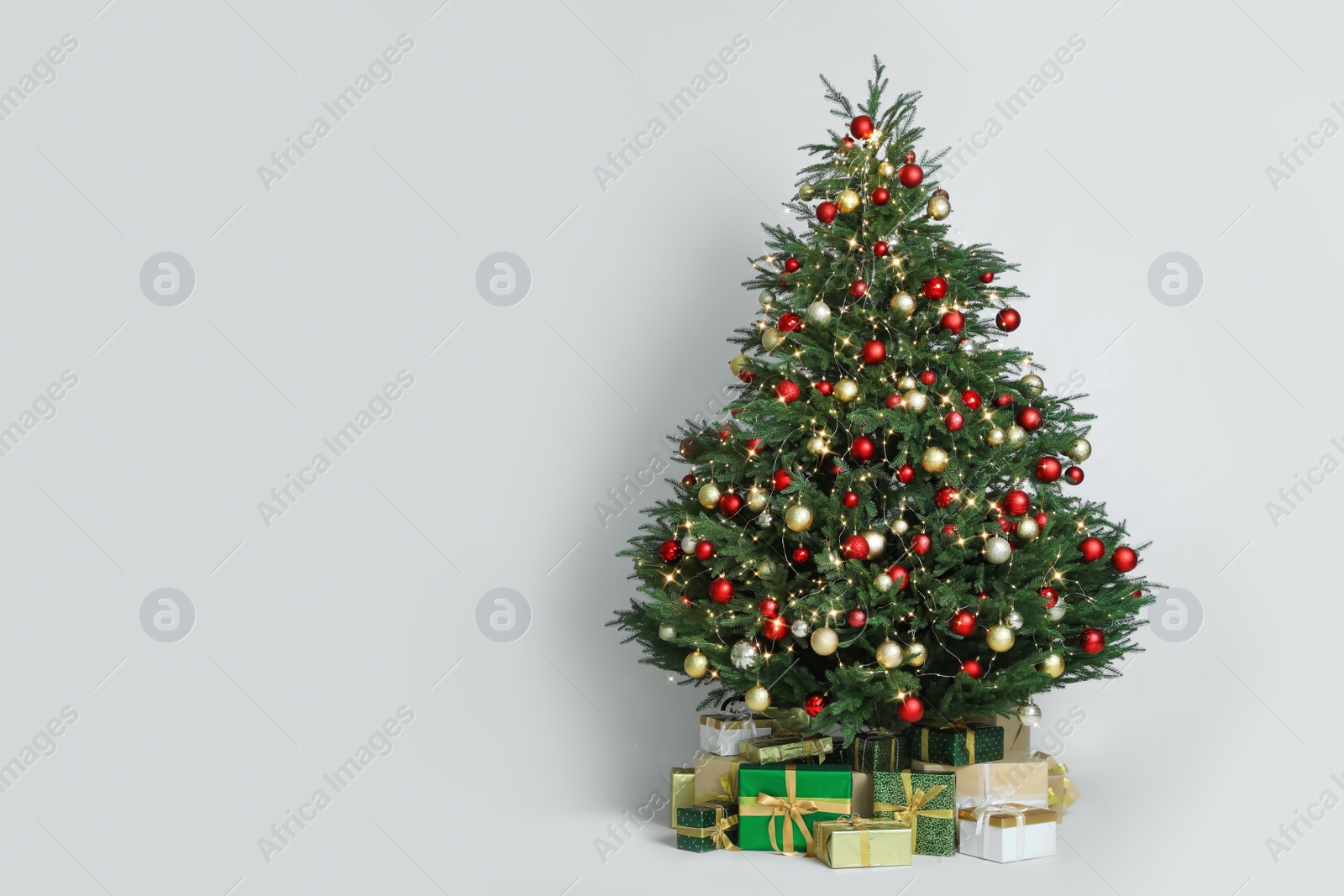 Photo of Beautiful Christmas tree with gift boxes on white background