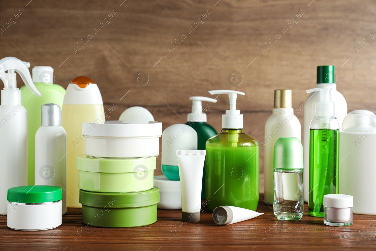 Photo of Different body care products on table against wooden background