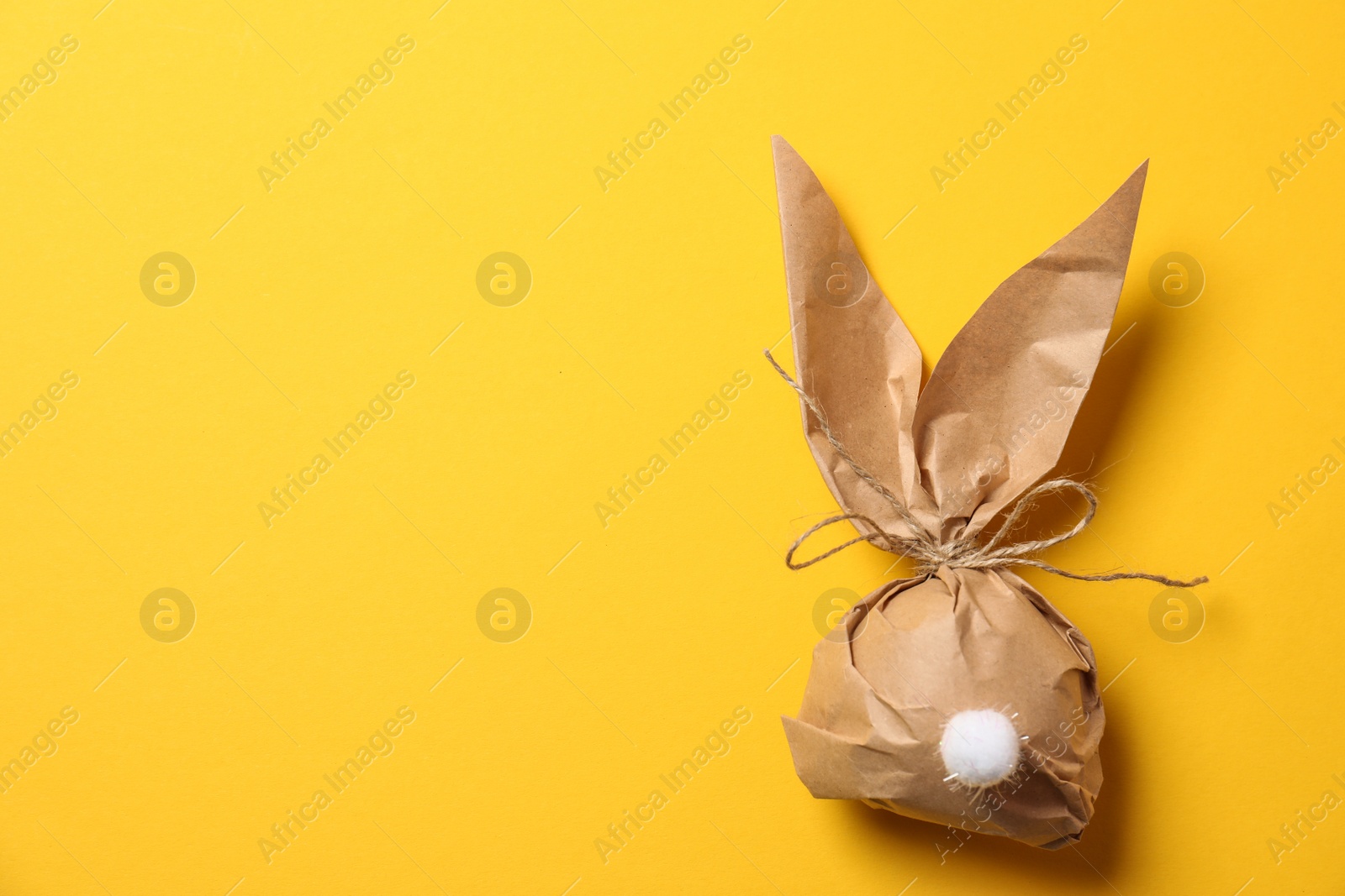 Photo of Creative Easter bunny gift bag on color background, top view with space for text