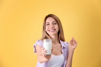 Beautiful young woman drinking milk on color background