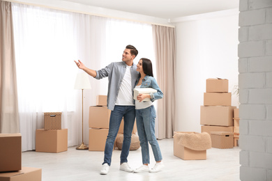 Photo of Happy couple in room with cardboard boxes on moving day