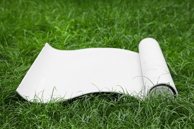 White karemat or fitness mat on green grass outdoors