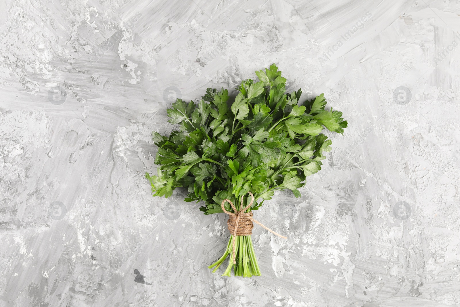 Photo of Bunch of fresh green parsley leaves on grey textured table, top view