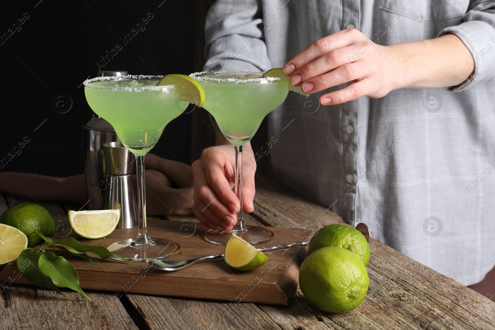 Photo of Woman making delicious Margarita cocktail at wooden table, closeup