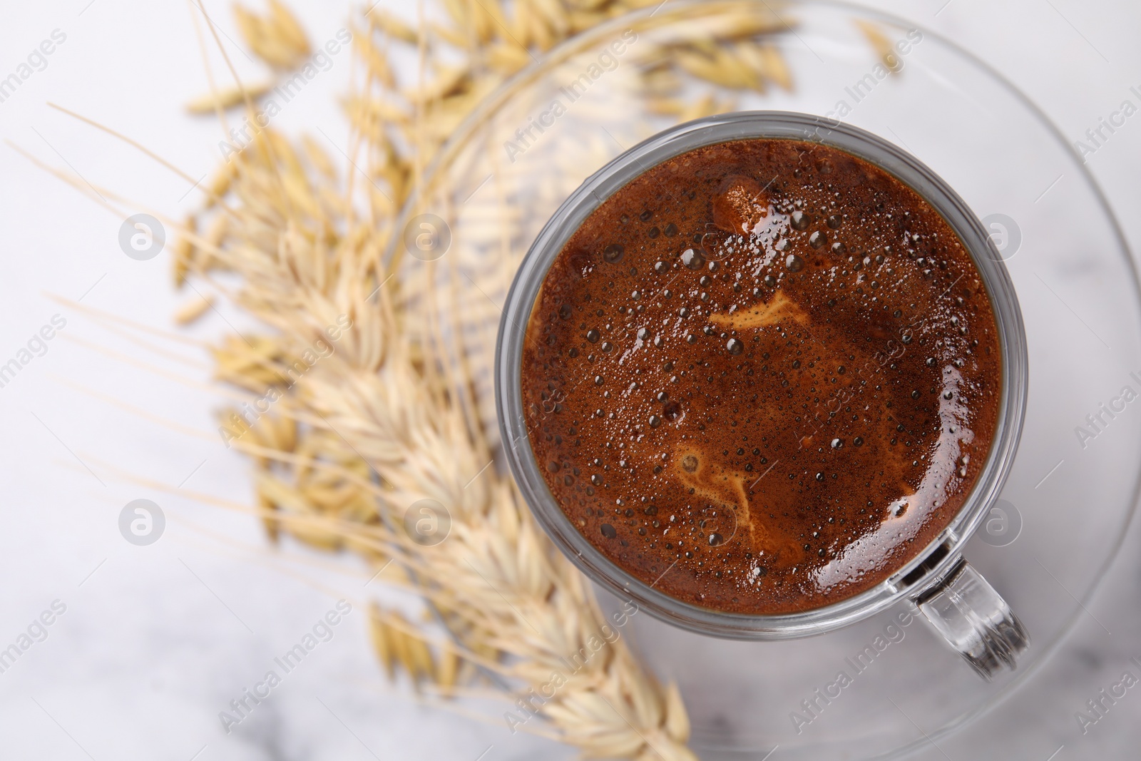 Photo of Cup of barley coffee, grains and spike on light table, top view