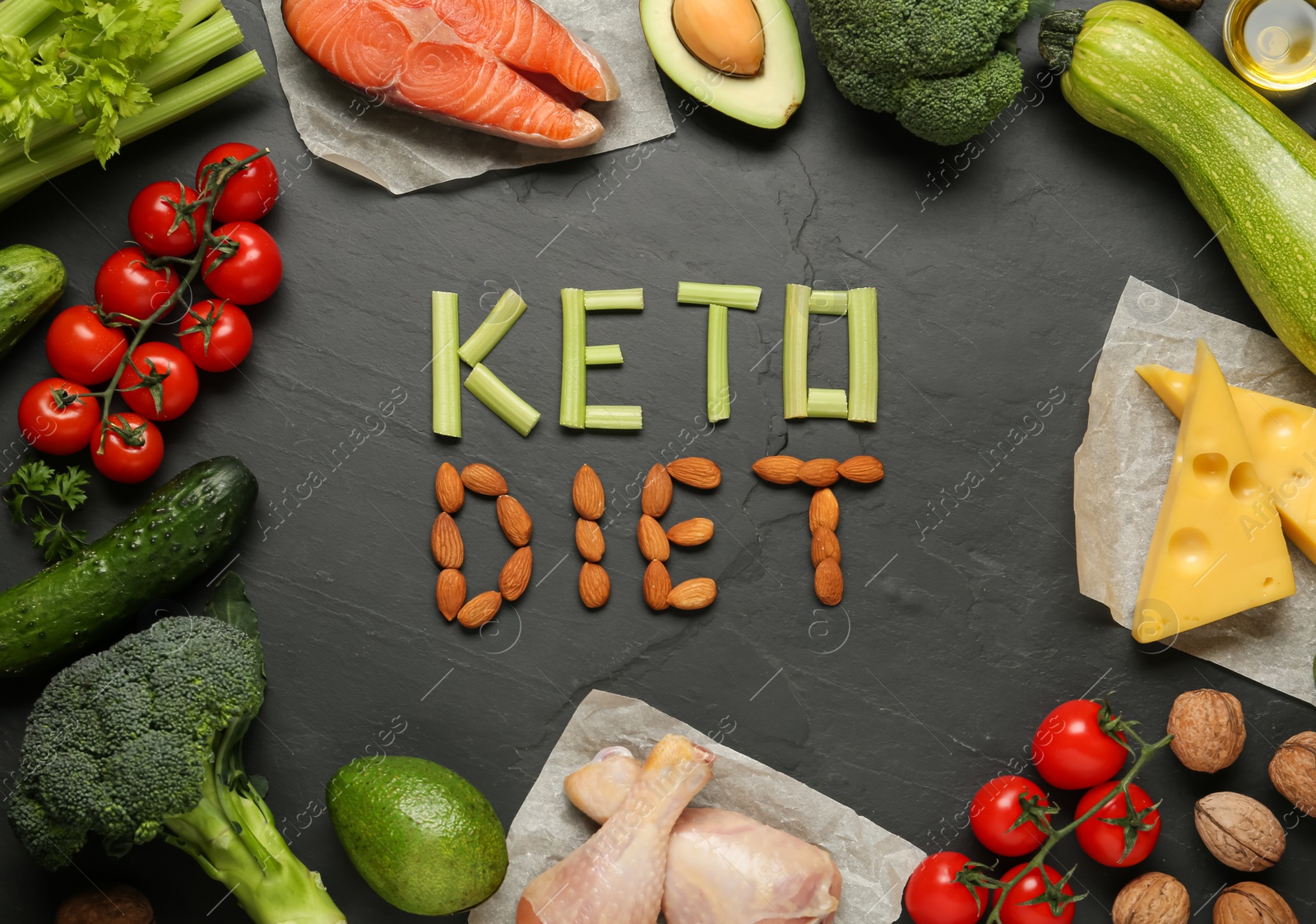 Photo of Words Keto Diet made of products surrounded by other food on black table, flat lay