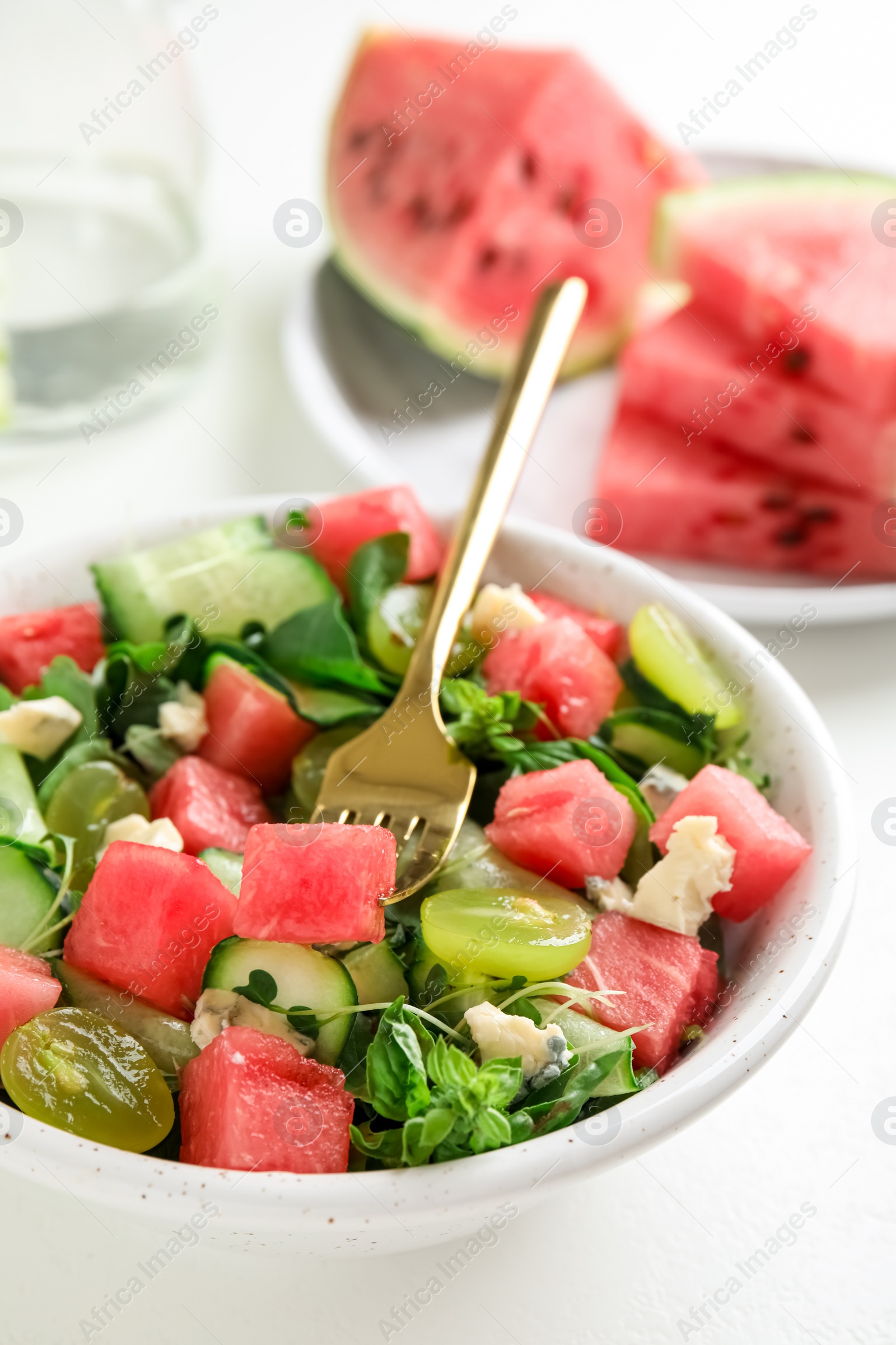 Photo of Delicious salad with watermelon served on white table, closeup