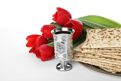 Photo of Passover matzos, silver goblet and flowers on white background. Pesach celebration